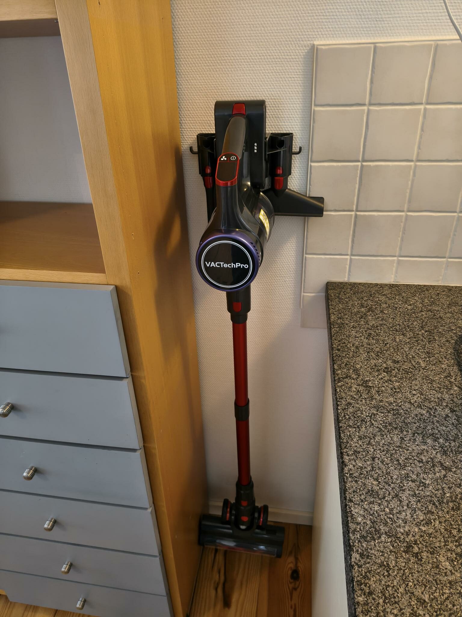 Akku‑Staubsauger an der Wandhalterung neben der Küchenzeile